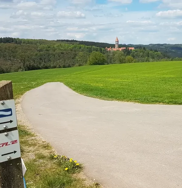 Markierung Eislek Trail mit Blick auf die Abtei Clervaux in Luxemburg