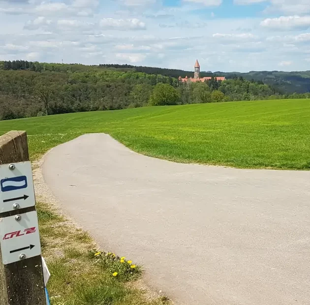 Markierung Eislek Trail mit Blick auf die Abtei Clervaux in Luxemburg
