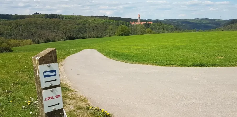 Markierung Eislek Trail mit Blick auf die Abtei Clervaux in Luxemburg