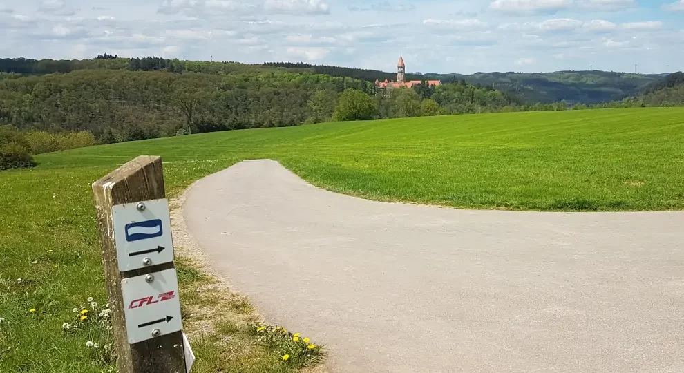 Markierung Eislek Trail mit Blick auf die Abtei Clervaux in Luxemburg