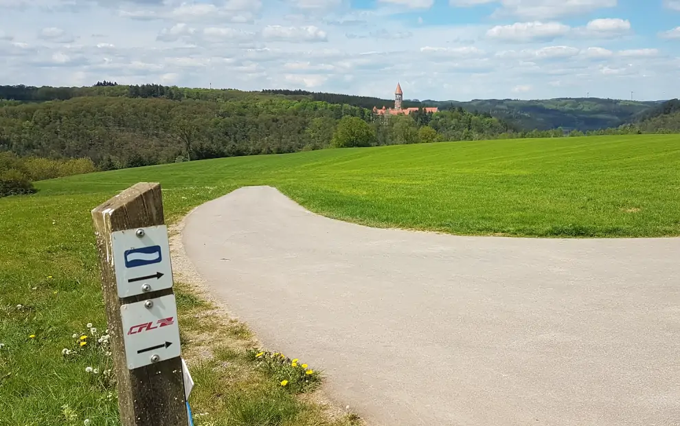 Markierung Eislek Trail mit Blick auf die Abtei Clervaux in Luxemburg